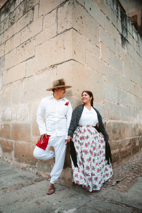Free Couple in traditional Mexican clothing posing against a historic stone wall in Oaxaca, México. Stock Photo