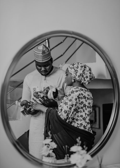 Free A Nigerian couple lovingly holds their baby in a mirror reflection, showcasing traditional attire. Stock Photo