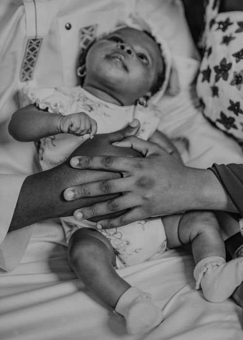 Free Black and white photo of parents lovingly cradling their newborn baby. Stock Photo