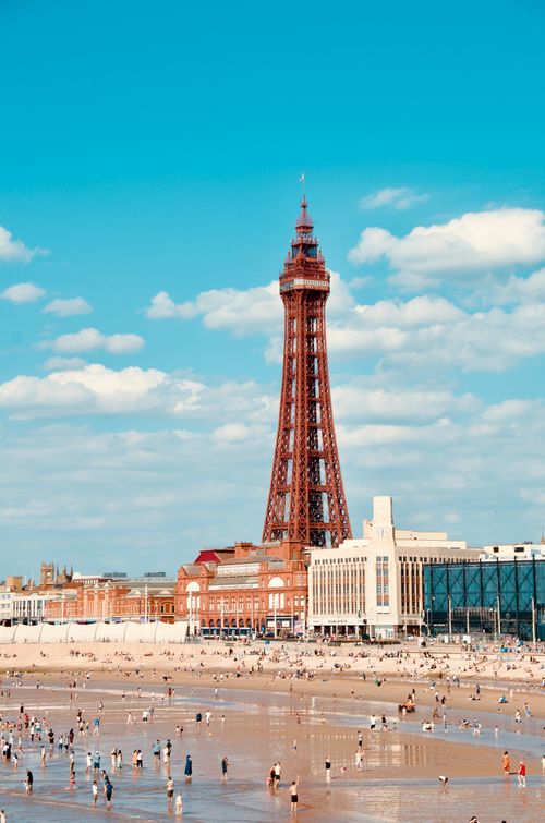 Free Vibrant summer day at Blackpool Tower with beachgoers enjoying the sun. Stock Photo