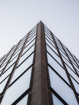 Upward view of a modern glass skyscraper with clear skies in New York City.
