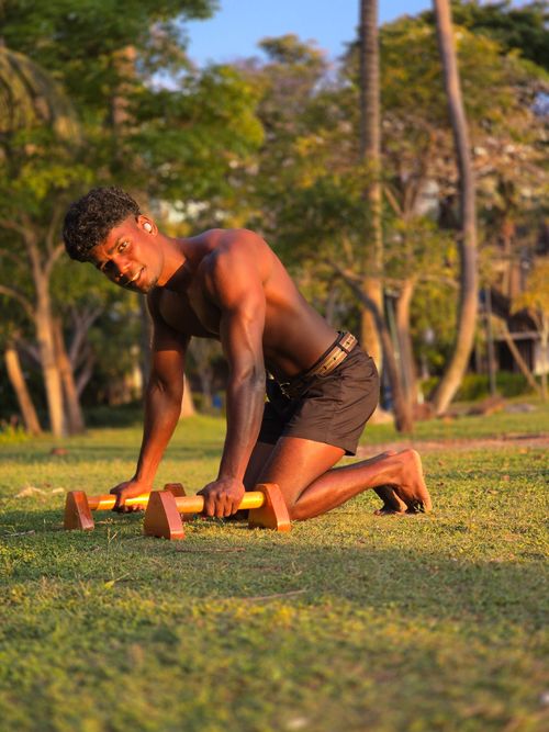 Free Athletic male performing calisthenics training outdoors in a Singapore park during golden hour. Stock Photo