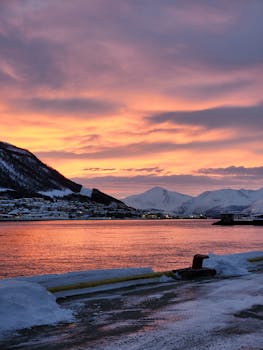 Breathtaking sunrise over a snow-covered fjord in Norway, capturing the vibrant colors and serene landscape.