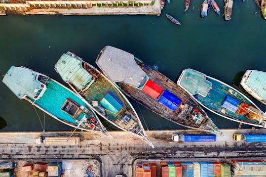 Bird's eye view of colorful boats docked at a marina, showcasing vibrant hues and industrial activity.