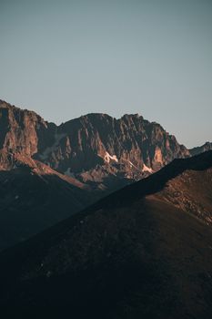 A striking view of a majestic mountain range during sunrise, showcasing warm tones and natural beauty.