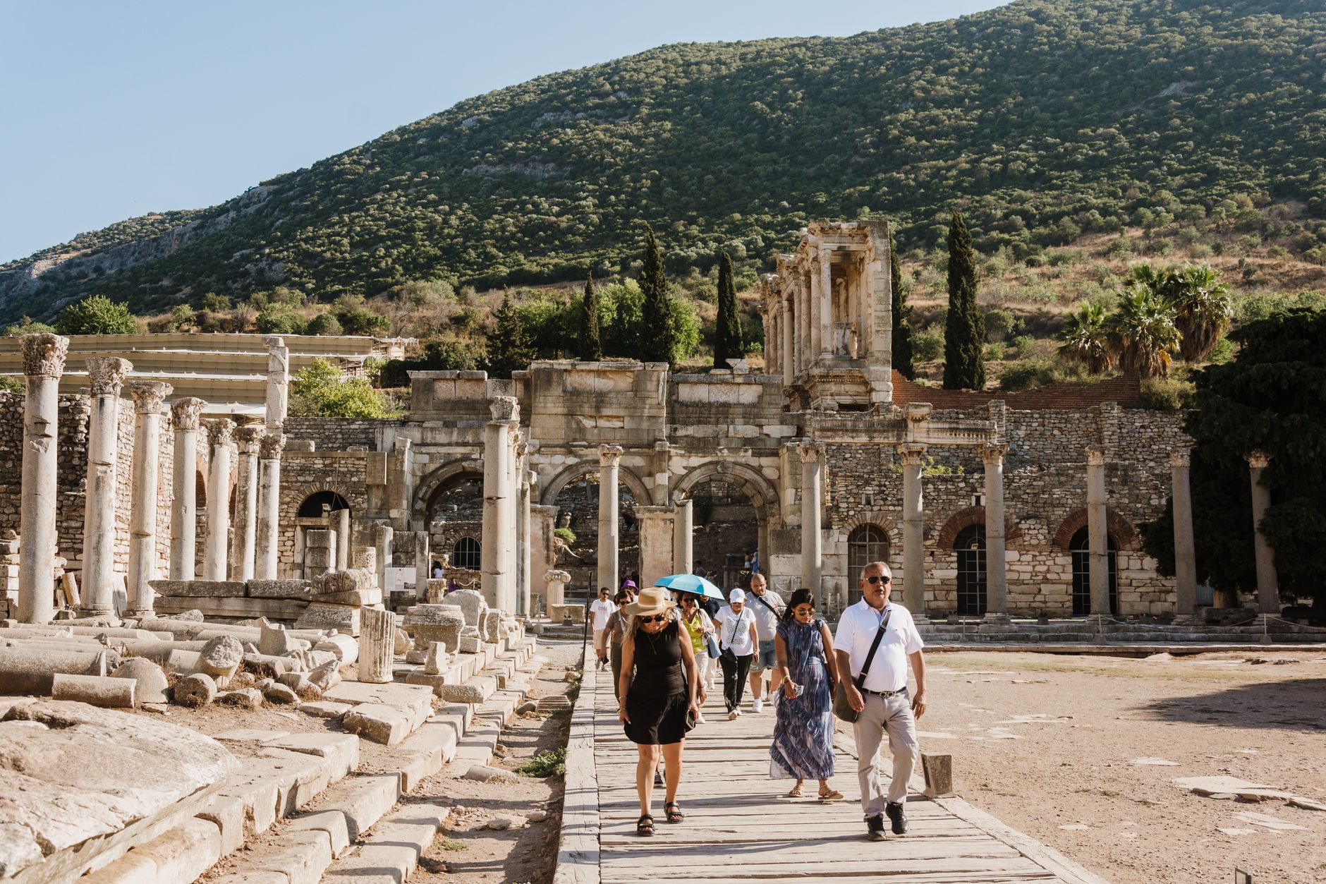 Tourists walk among ancient ruins in Ephesus, highlighting historical architecture and vibrant atmosphere.