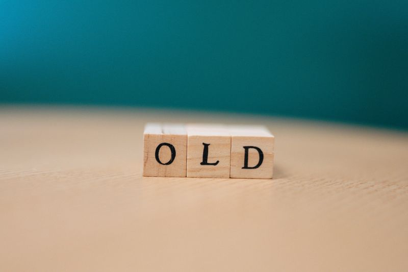 Wooden blocks on a table spelling "OLD" with a plain background.