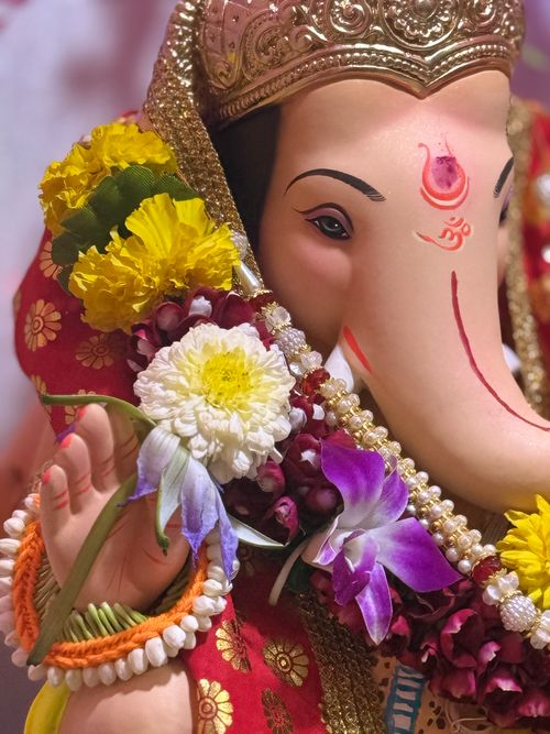 Free Colorful Ganesh statue enriched with diverse vibrant flowers, symbolizing divinity and festivity. Stock Photo