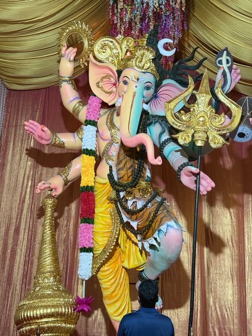 Free Colorful statue of Lord Ganesha adorned for a festival with a devotee nearby. Stock Photo