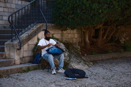 A street musician plays a handpan in an outdoor urban setting, creating a serene ambiance.