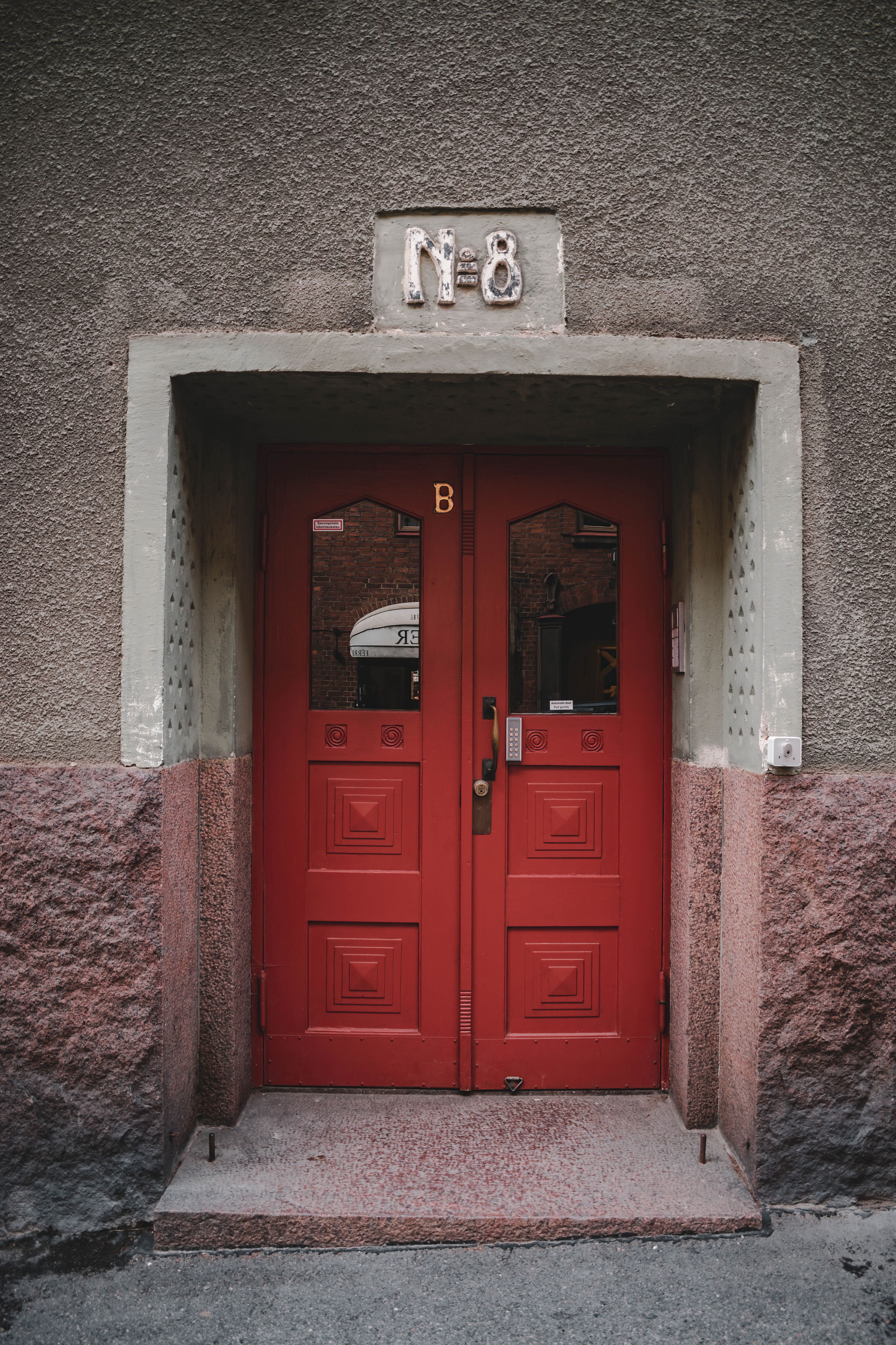 Bold red double doors with number 8 in Helsinki, showcasing classic urban architecture style.