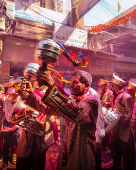 Vibrant street parade with traditionally dressed musicians in India, celebrating with music and colors.
