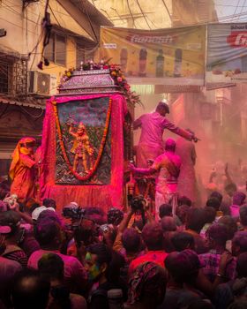 Colorful Holi festival celebration with crowds in India, covered in vibrant powders.