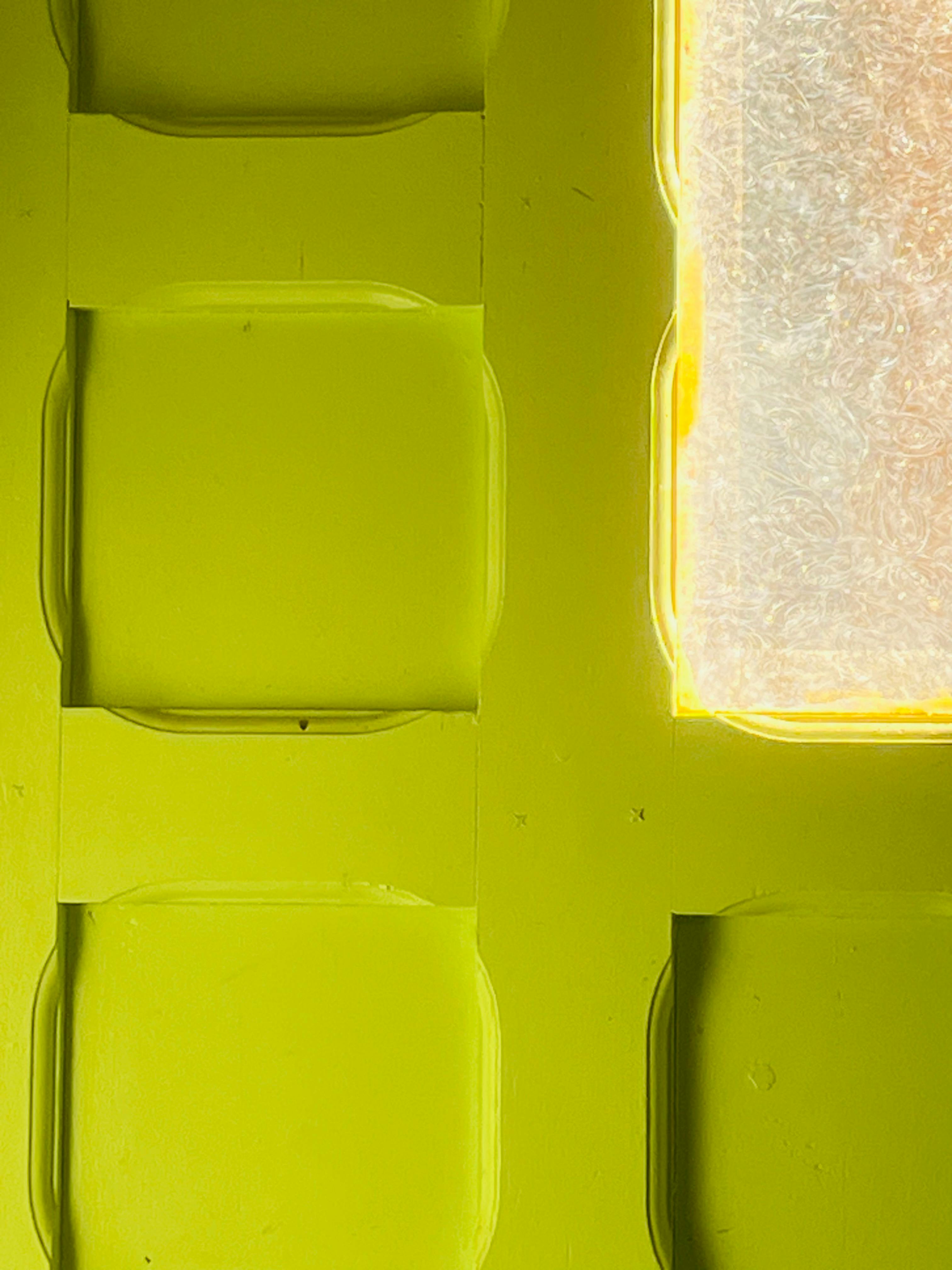 무료 빛이 질감 있는 표면을 통해 흘러나오는 생생한 노란색의 기하학적 벽 패턴입니다. 스톡 사진