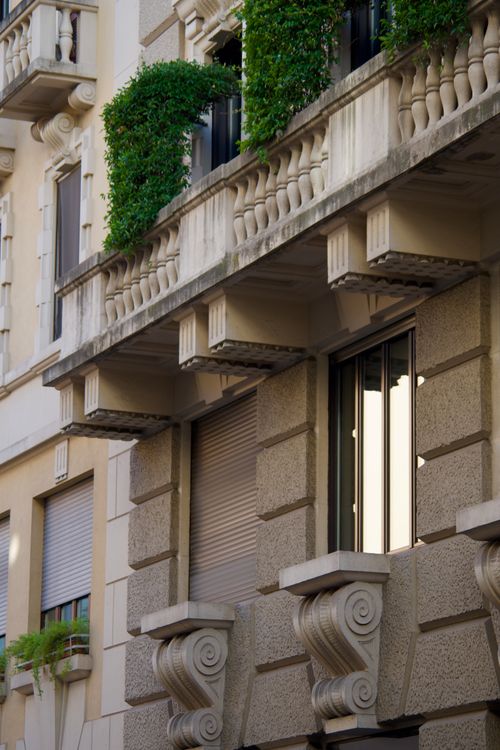 Free Elegantly detailed urban building facade with lush greenery and classic architectural designs. Stock Photo