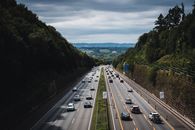 A bustling highway cuts through lush forests under a cloudy sky in Herford, Germany.