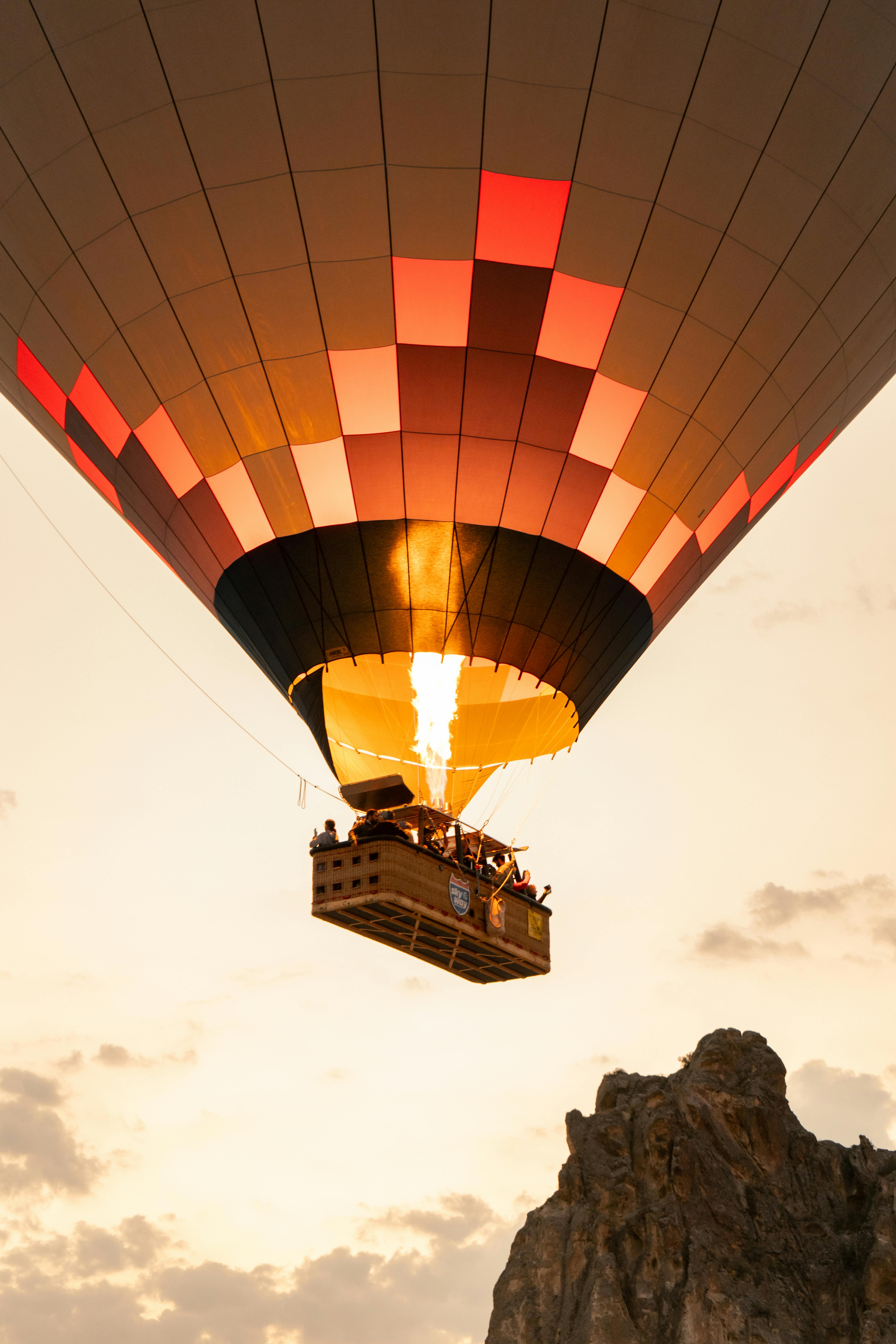 Scenic hot air balloon flight over a rocky cliff during sunset, highlighting adventure and travel.