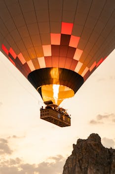 Scenic hot air balloon flight over a rocky cliff during sunset, highlighting adventure and travel.