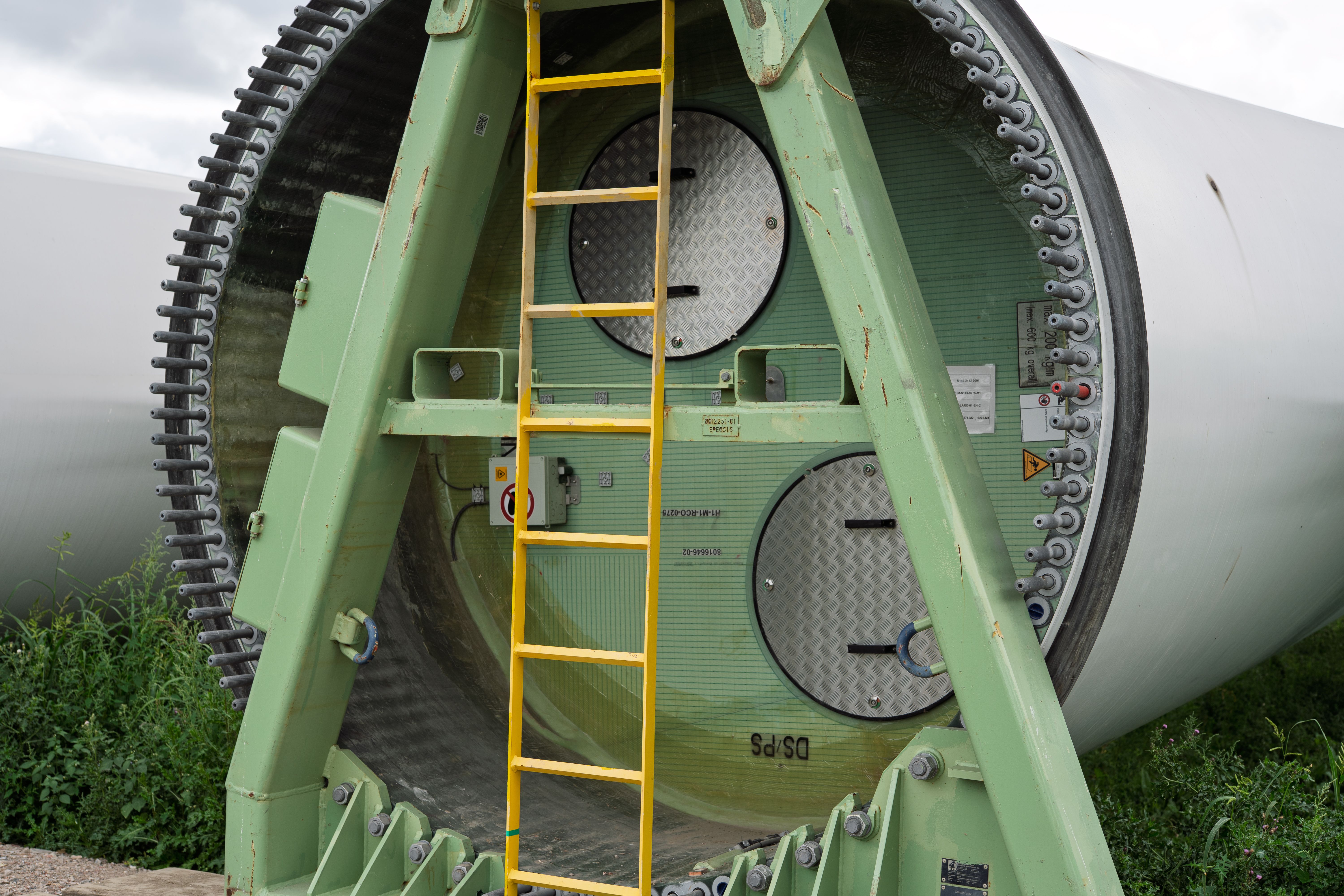 Close-up of a wind turbine section with a ladder attached, showcasing industrial design.