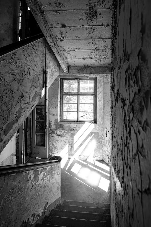 Free Sunlight streaming through an old window illuminates an abandoned stairwell in Chemnitz. Stock Photo