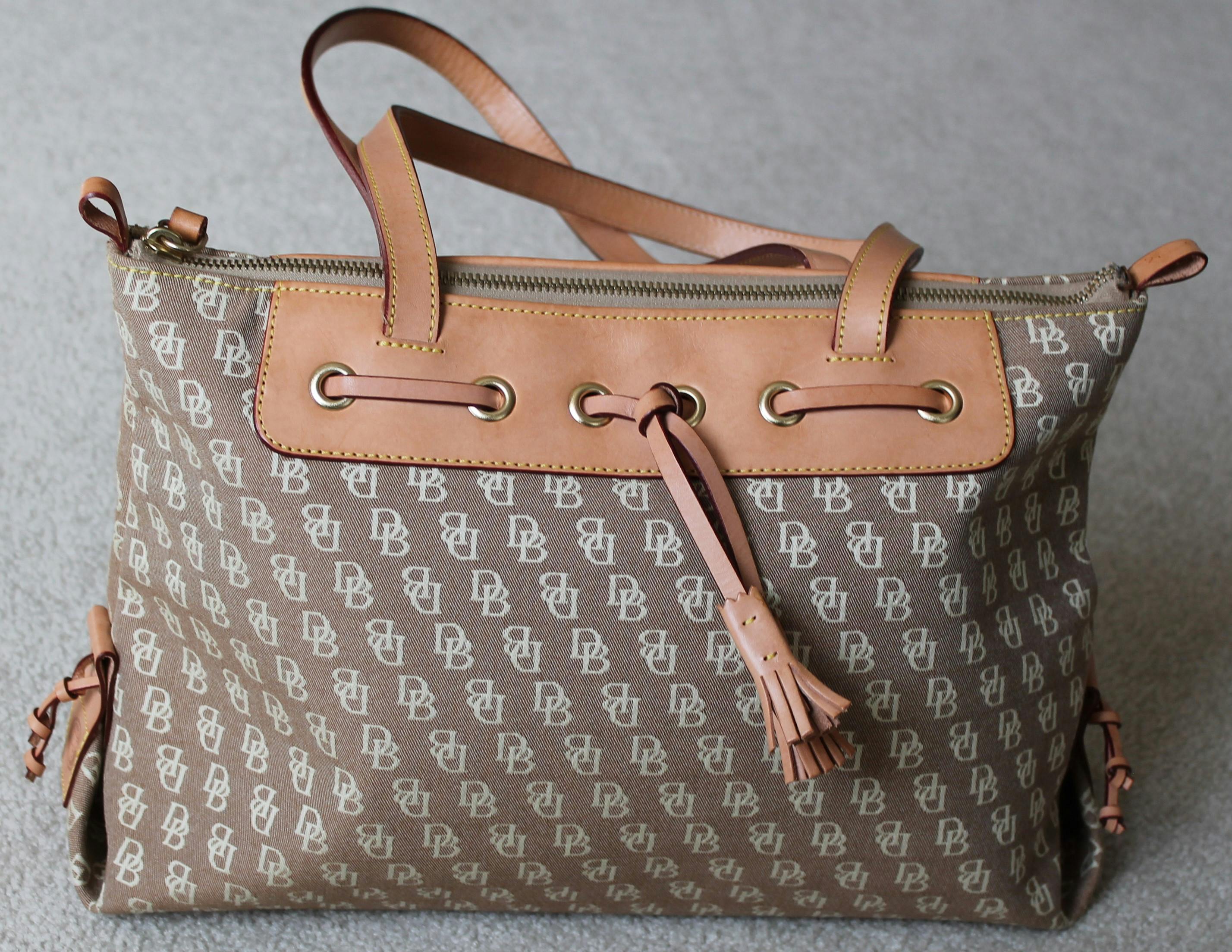 Stylish Dooney & Bourke tote bag featuring beige canvas and leather trim, perfect for fashion enthusiasts.