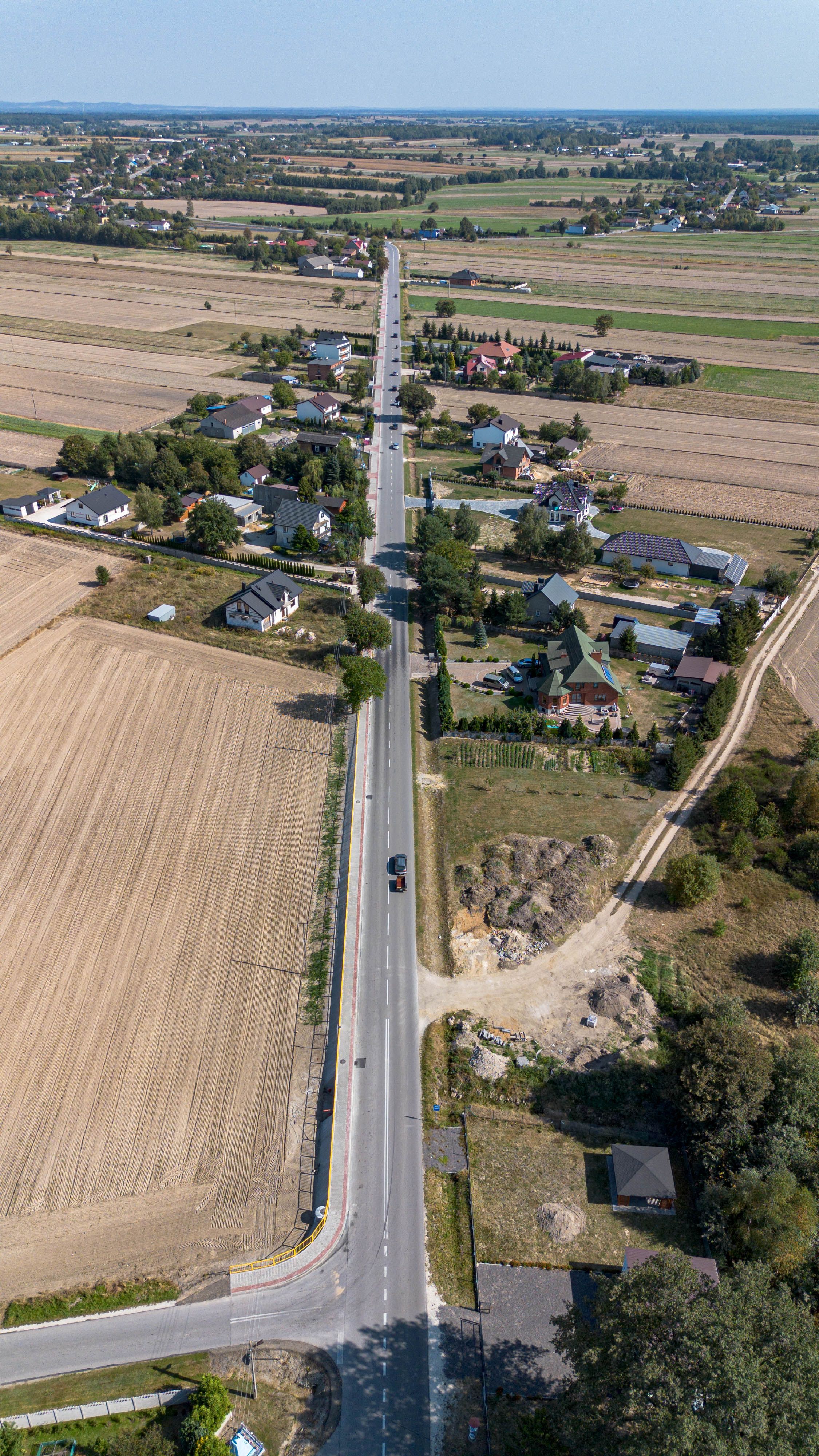 Aerial photo showcasing a long straight road amidst rural landscapes and fields.
