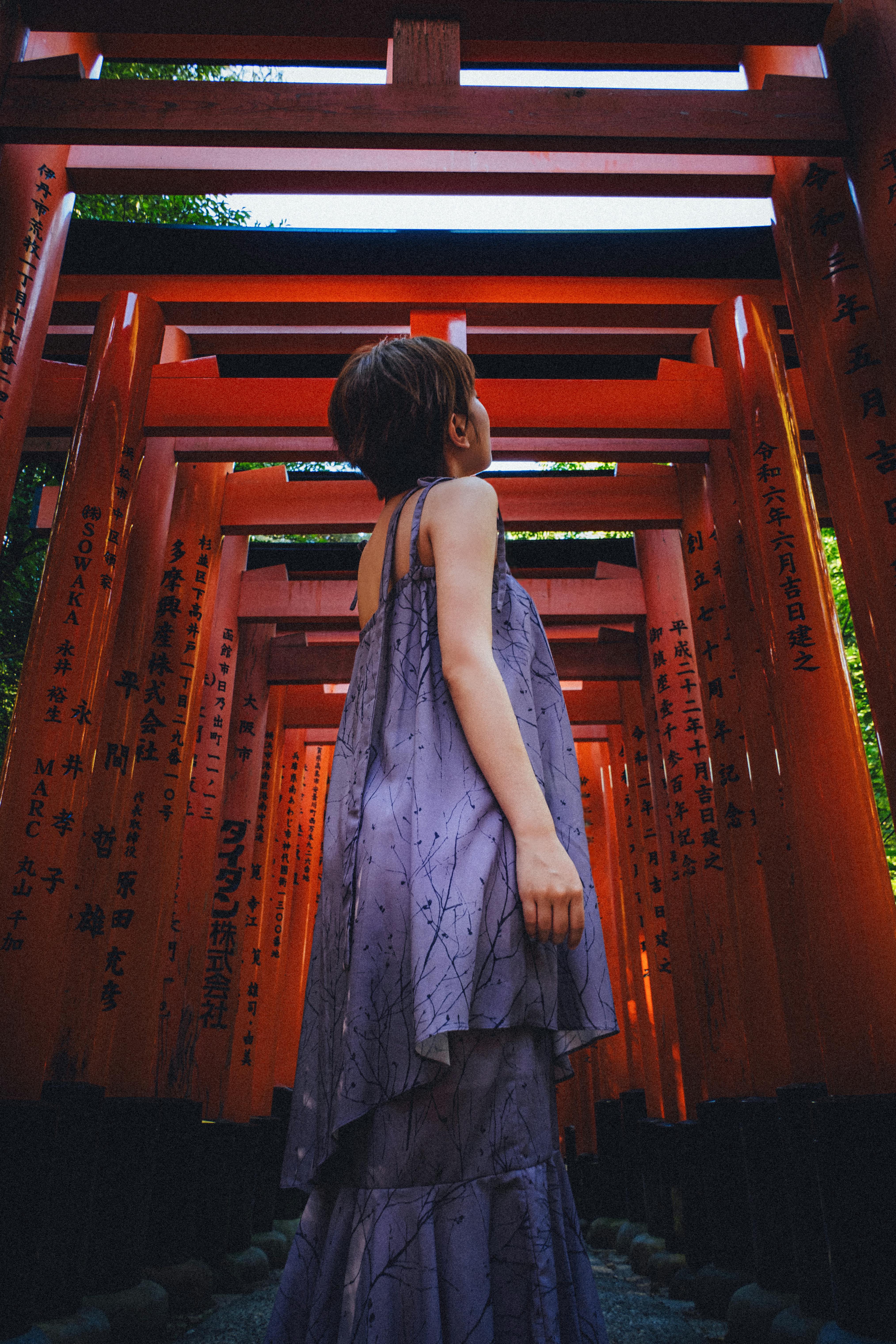 Woman in a purple dress exploring the vibrant red Torii gates in Kyoto, Japan.