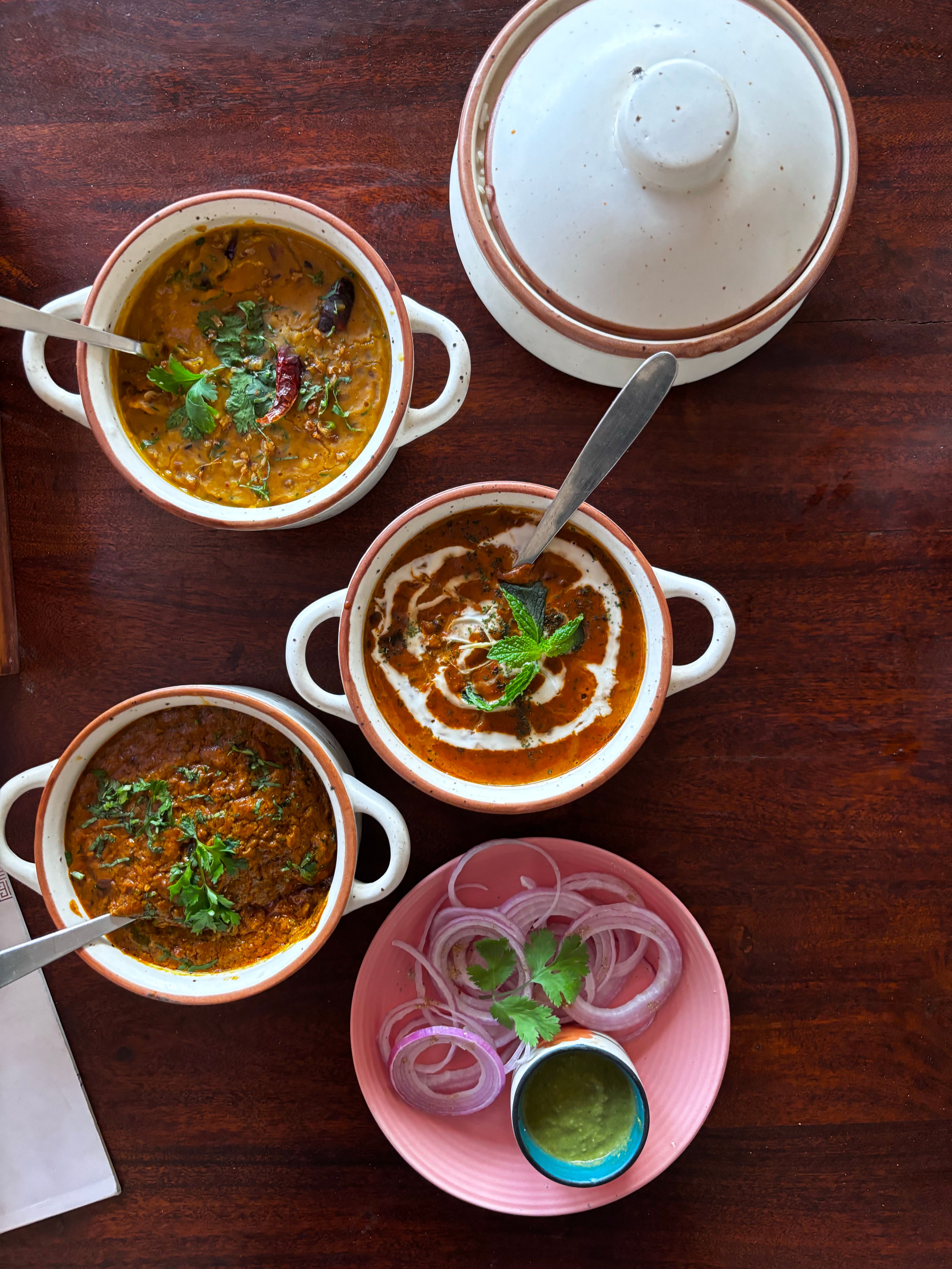 Top view of traditional Indian lentil dishes with spices and garnishes, perfect for culinary use.