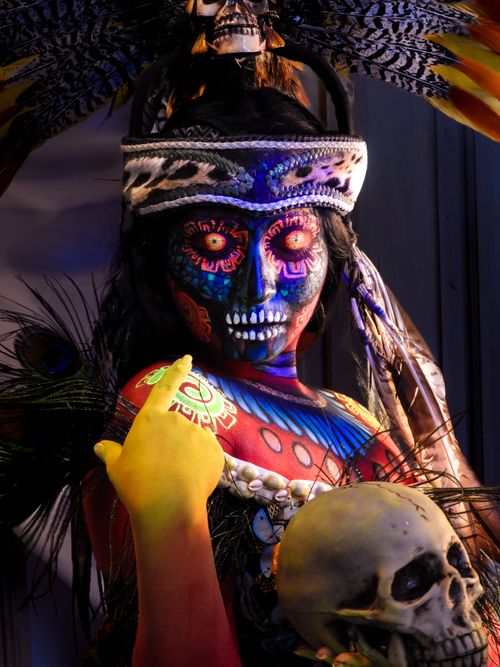 Free Colorful Dia de los Muertos-themed portrait with intricate face painting and skull props. Captures cultural richness. Stock Photo