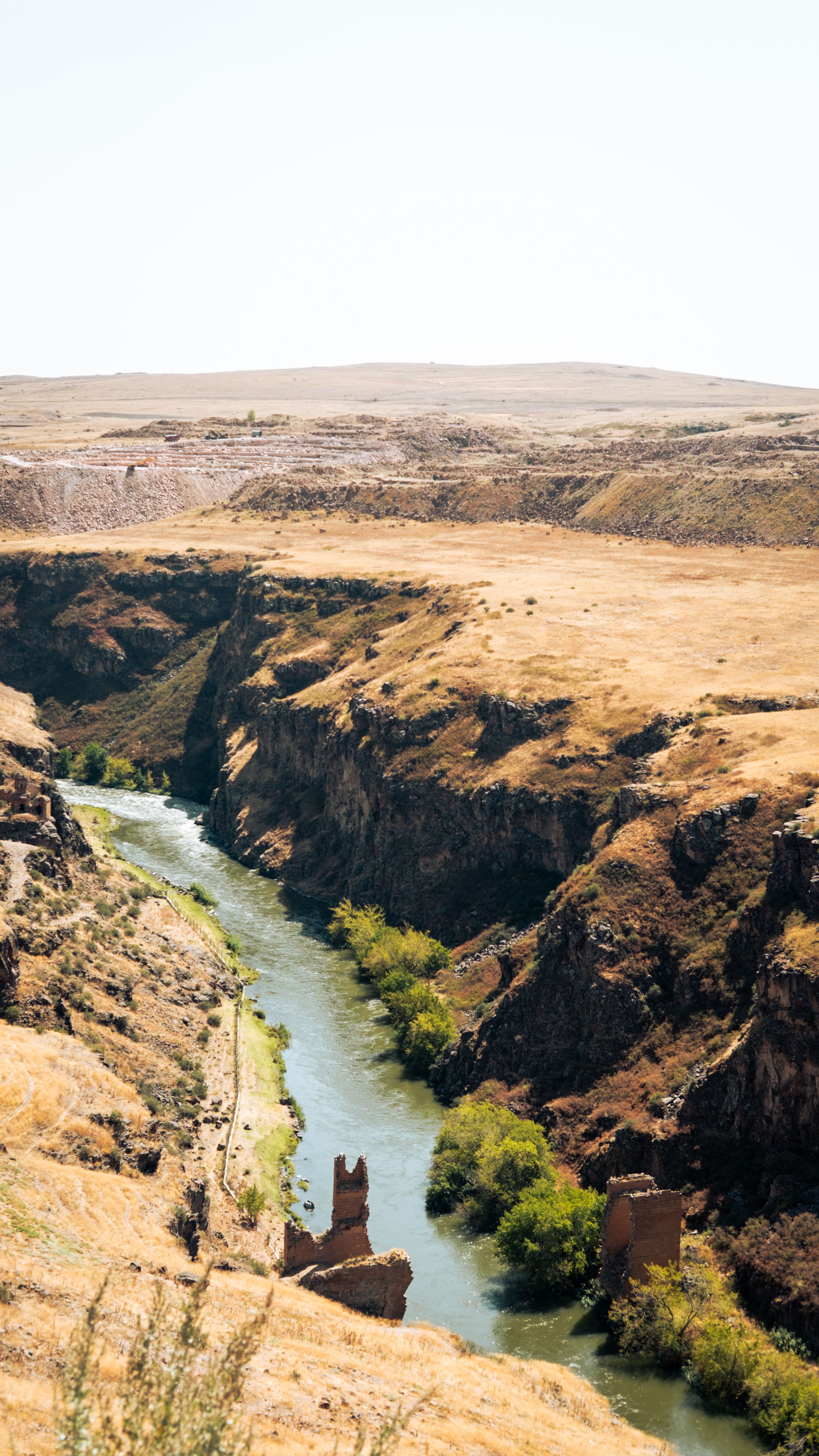 An aerial view of a river winding through a canyon in a dry, arid landscape.