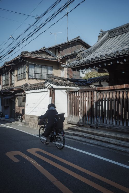 Free A cyclist traverses a traditional Kyoto street lined with historic architecture, exemplifying Japan's unique cultural blend. Stock Photo