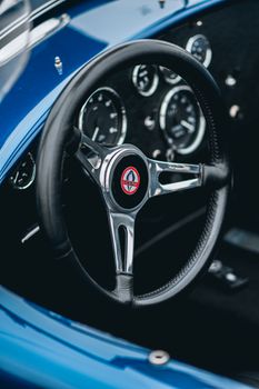 Close-up of a classic car's steering wheel and dashboard showcasing vintage charm.
