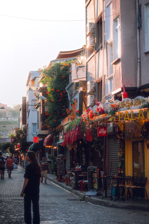 Free Picturesque cobblestone street lined with vibrant cafes at sunset. Stock Photo