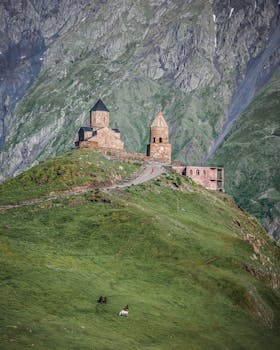 View of Gergeti Trinity Church against the stunning Caucasus Mountains landscape in Georgia.