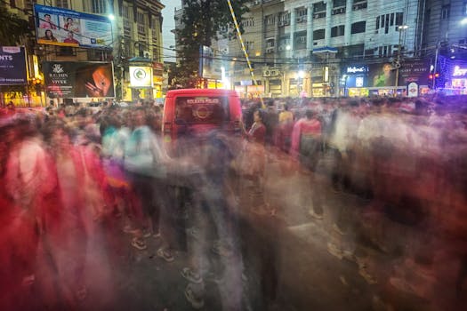 A vibrant street scene in Kolkata with blurred motion of people at night.
