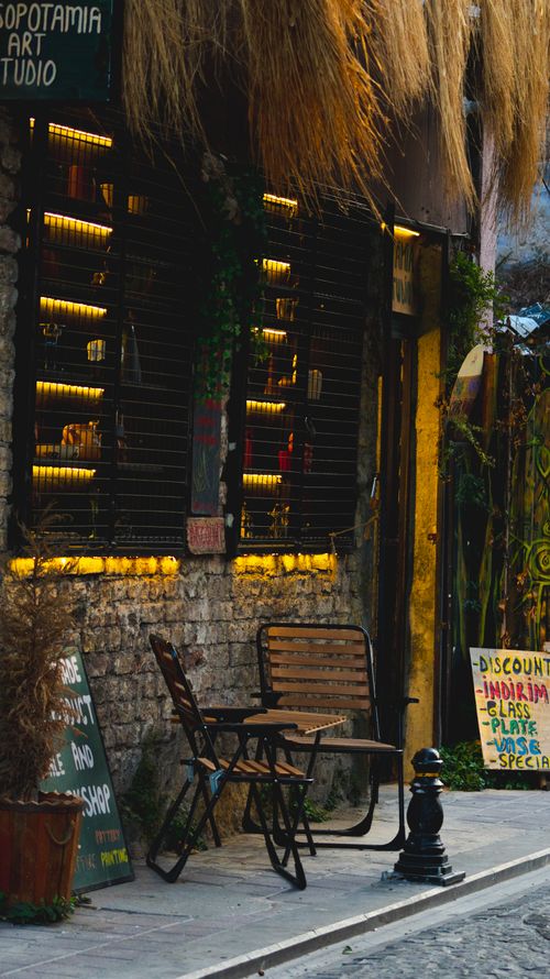 Free Cozy outdoor café setting with warm lights and rustic decor on a charming street at dusk. Stock Photo