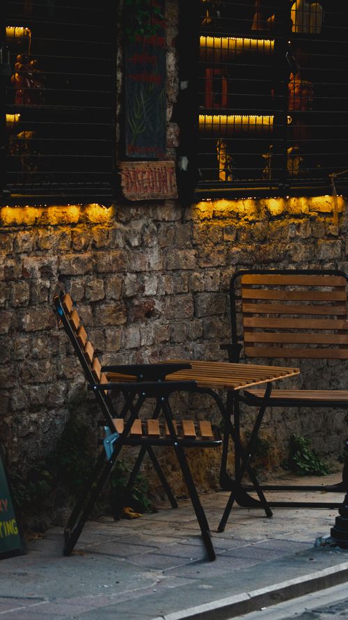 Free Wooden chairs and table in a cozy outdoor cafe setting, evening ambiance. Stock Photo
