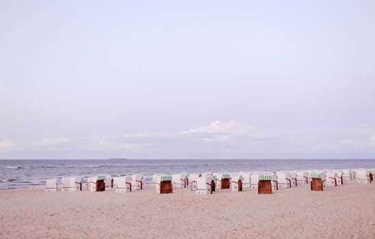 Tranquil beach scene at dusk in Mecklenburg-Vorpommern, Germany, featuring iconic strandkörbe.