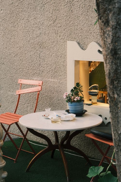 Free A cozy outdoor café table setup with chairs and a potted plant, perfect for relaxed moments. Stock Photo