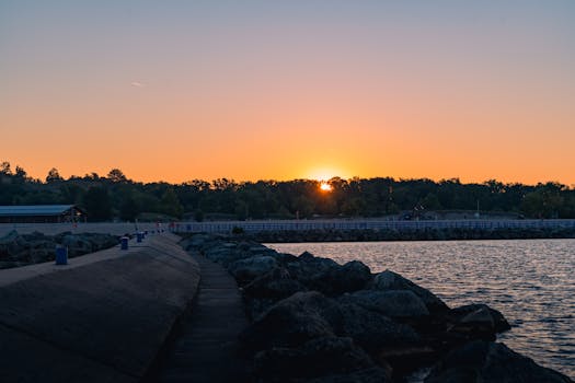 Captivating sunrise over a peaceful beach and pier in Holland, Michigan, with a fiery orange sky.