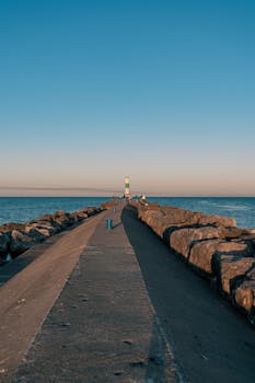 Scenic view of a green lighthouse at sunrise on Holland Pier, Michigan, overlooking Lake Michigan.