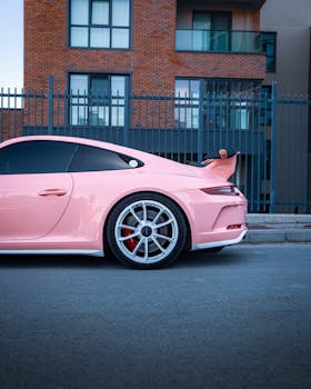Sleek pink sports car parked against a modern building in Ankara, Türkiye.