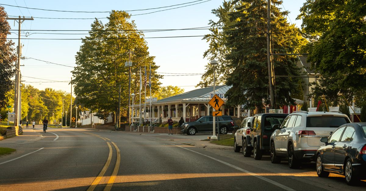 Cozy street view in Holland, Michigan showcasing parked cars, trees, and clear evening light.