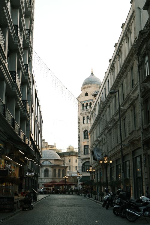 Free Charming cobblestone street with historic architecture and cafe shops in a city setting. Stock Photo