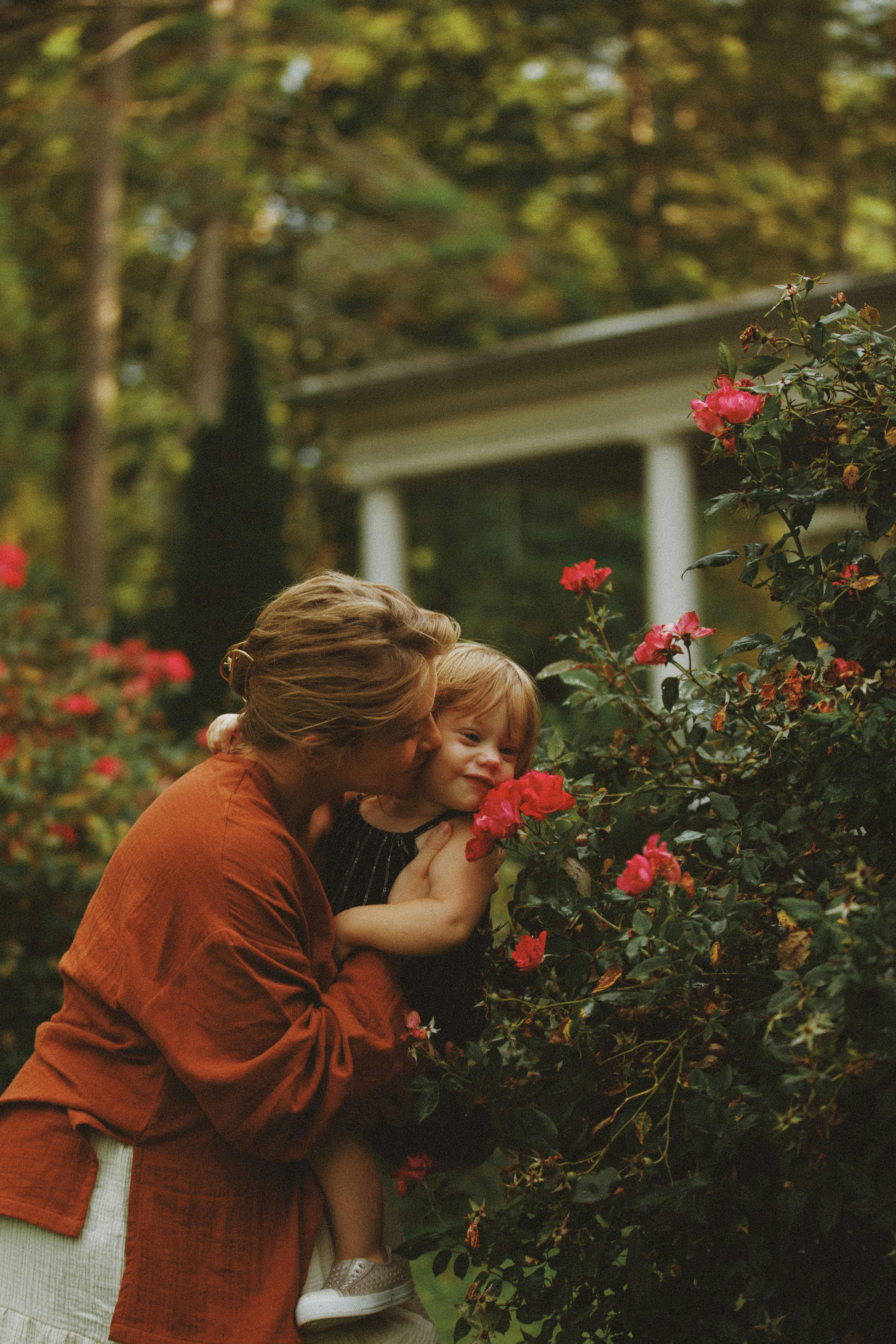 A loving moment between a mother and child surrounded by vibrant flowers in a serene garden.