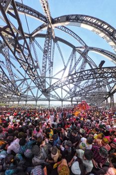 Crowds gather for a vibrant festival under the iconic Howrah Bridge in Kolkata.