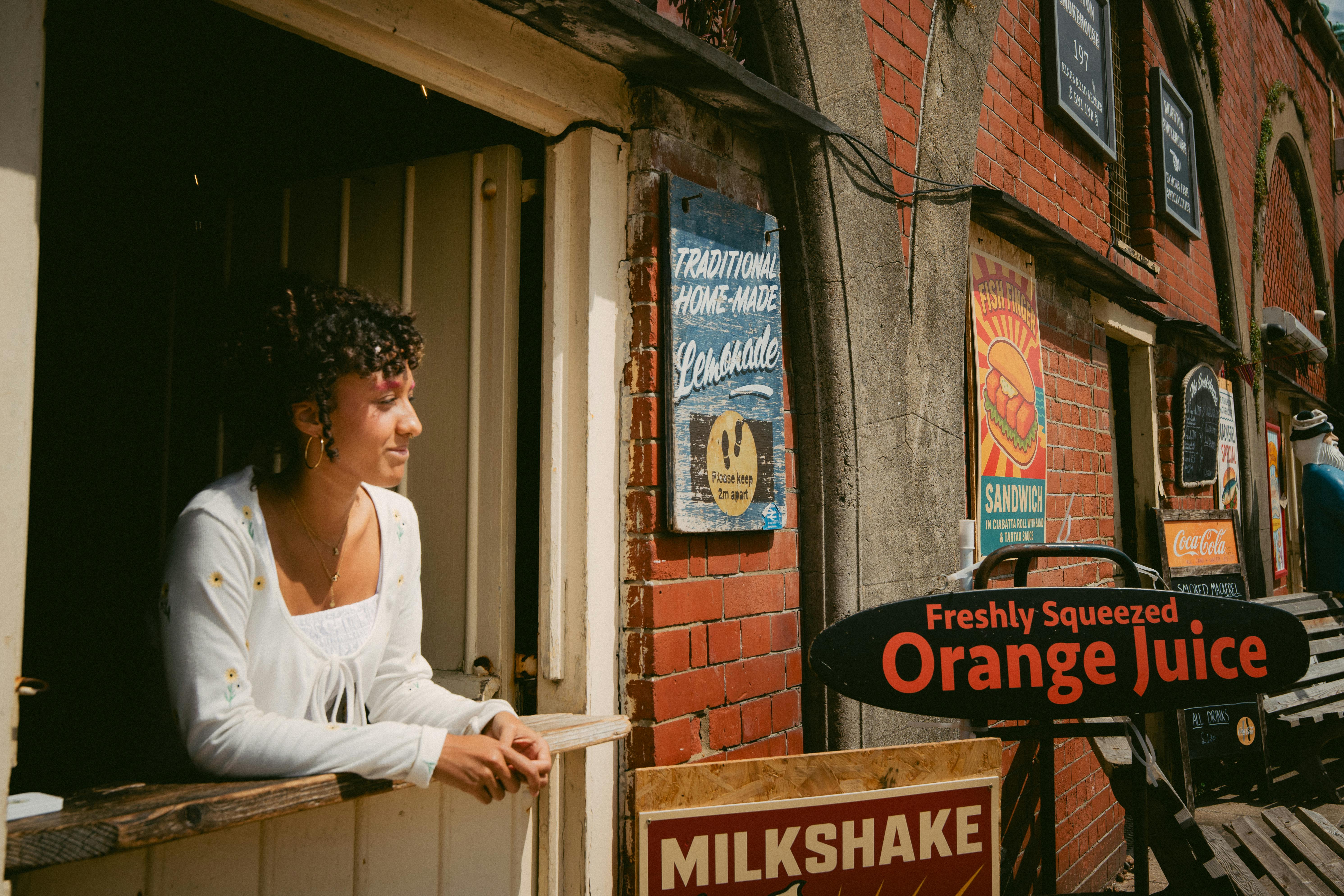 A woman relaxes by a market stall with vintage signs in Brighton, England.