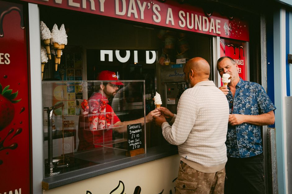 Two men enjoy ice cream at a seaside stall in Brighton and Hove, England.