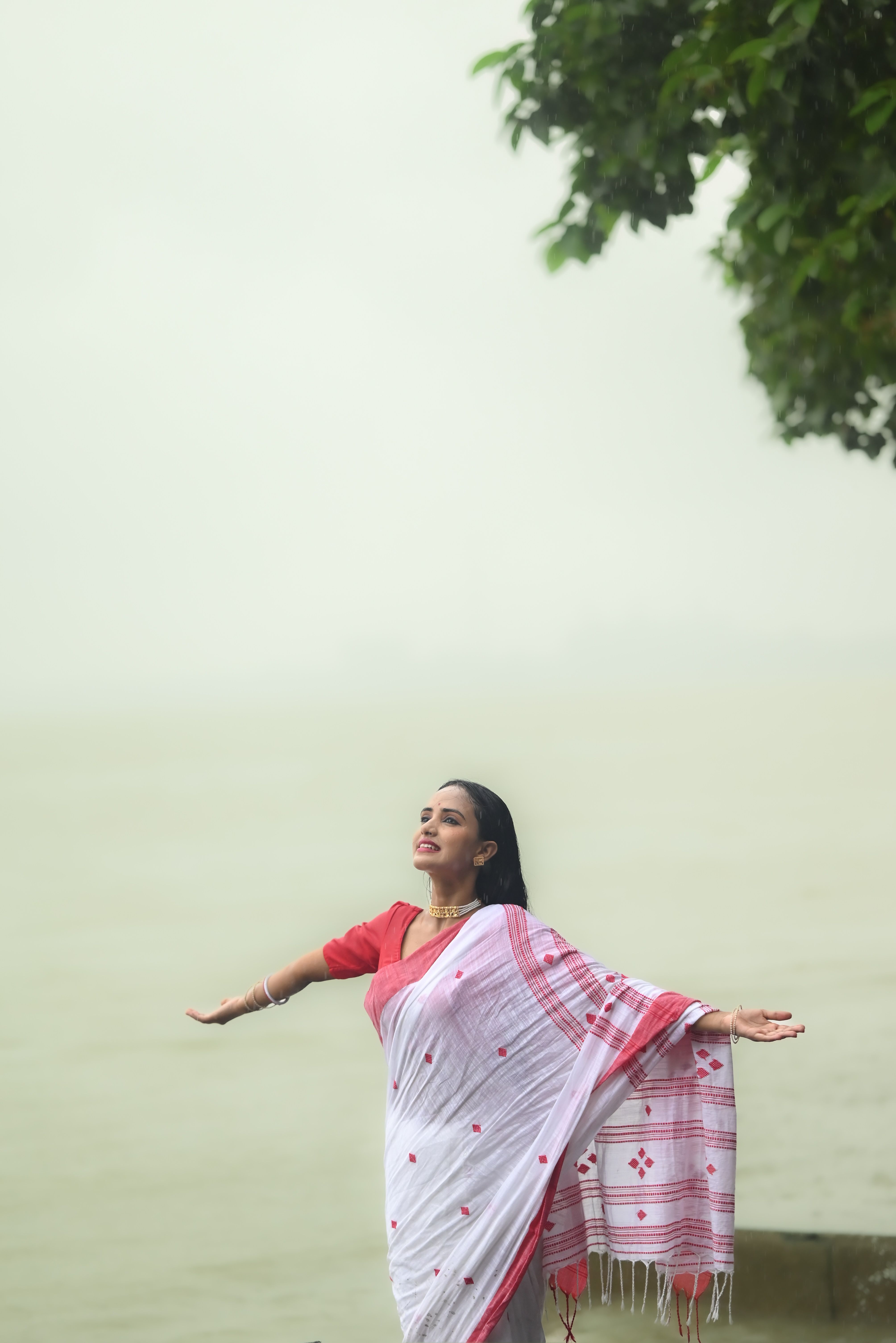 Woman in traditional Indian sari enjoys moment by a serene lakeside.