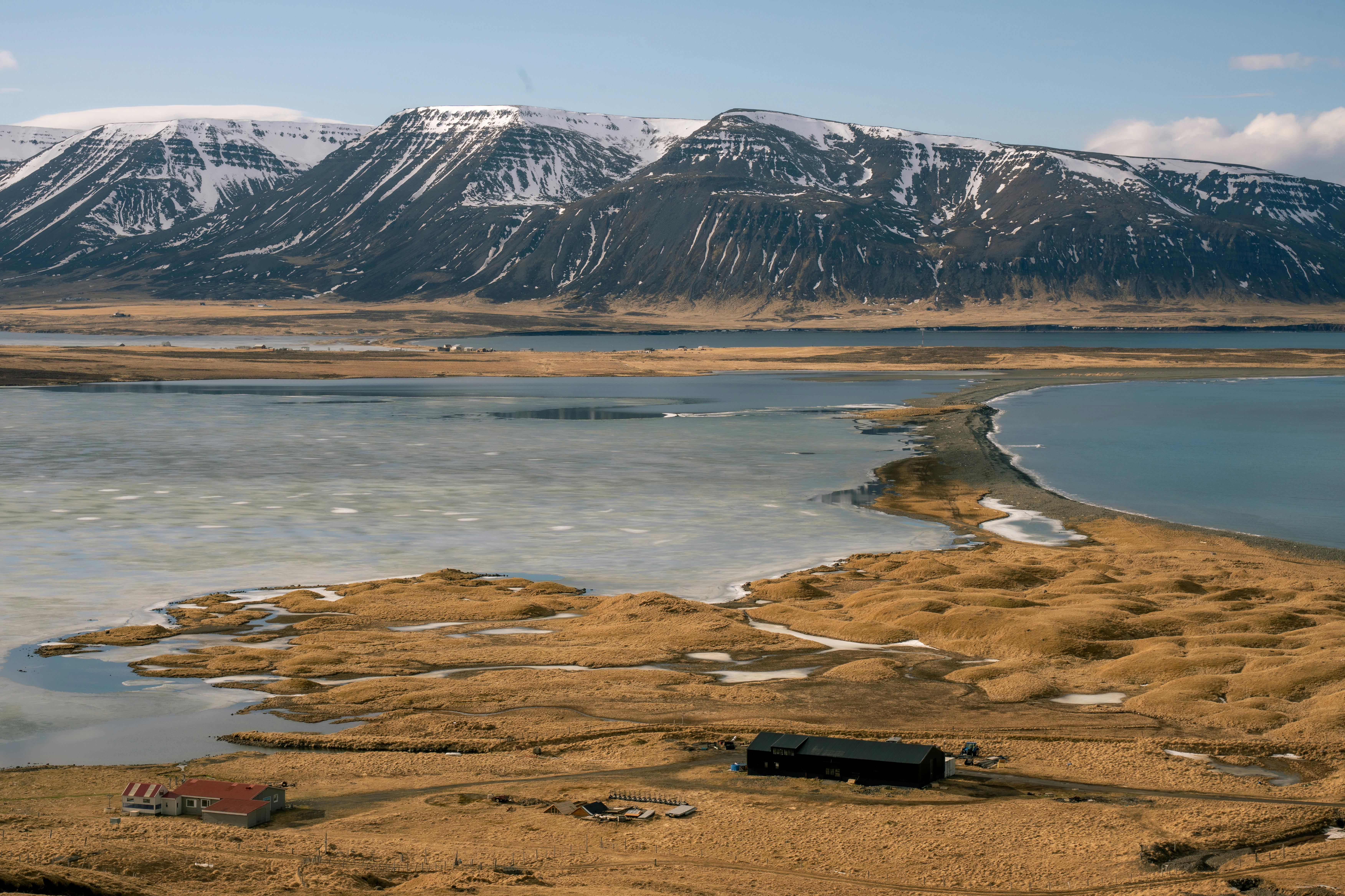 Captivating view of Icelandic mountains over a calm lake and rugged plains in early spring.